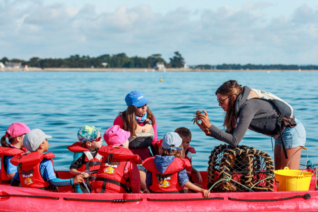 monitrice de voile montrant un petit crabe à des jeunes enfants
