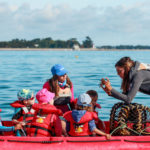 monitrice de voile montrant un petit crabe à des jeunes enfants