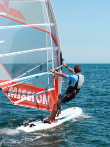 Véliplanchiste de dos sur une planche à voile à voile orange à Loctudy