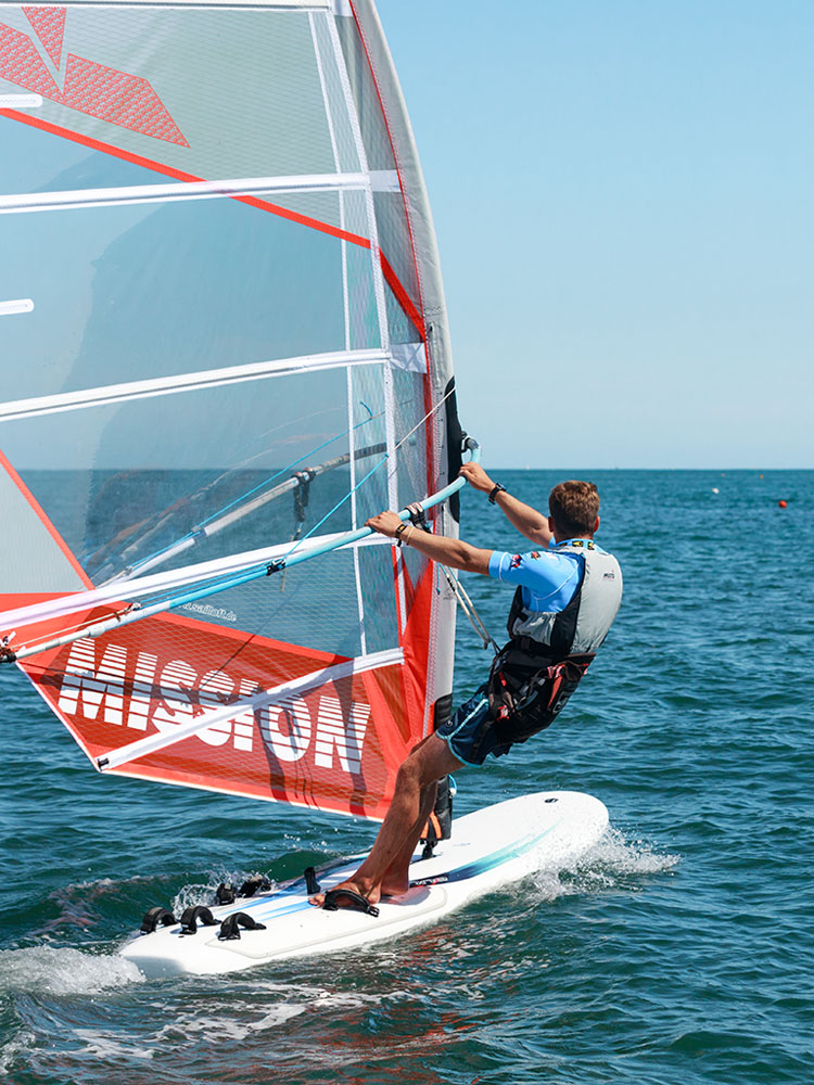 Véliplanchiste de dos sur une planche à voile à voile orange à Loctudy